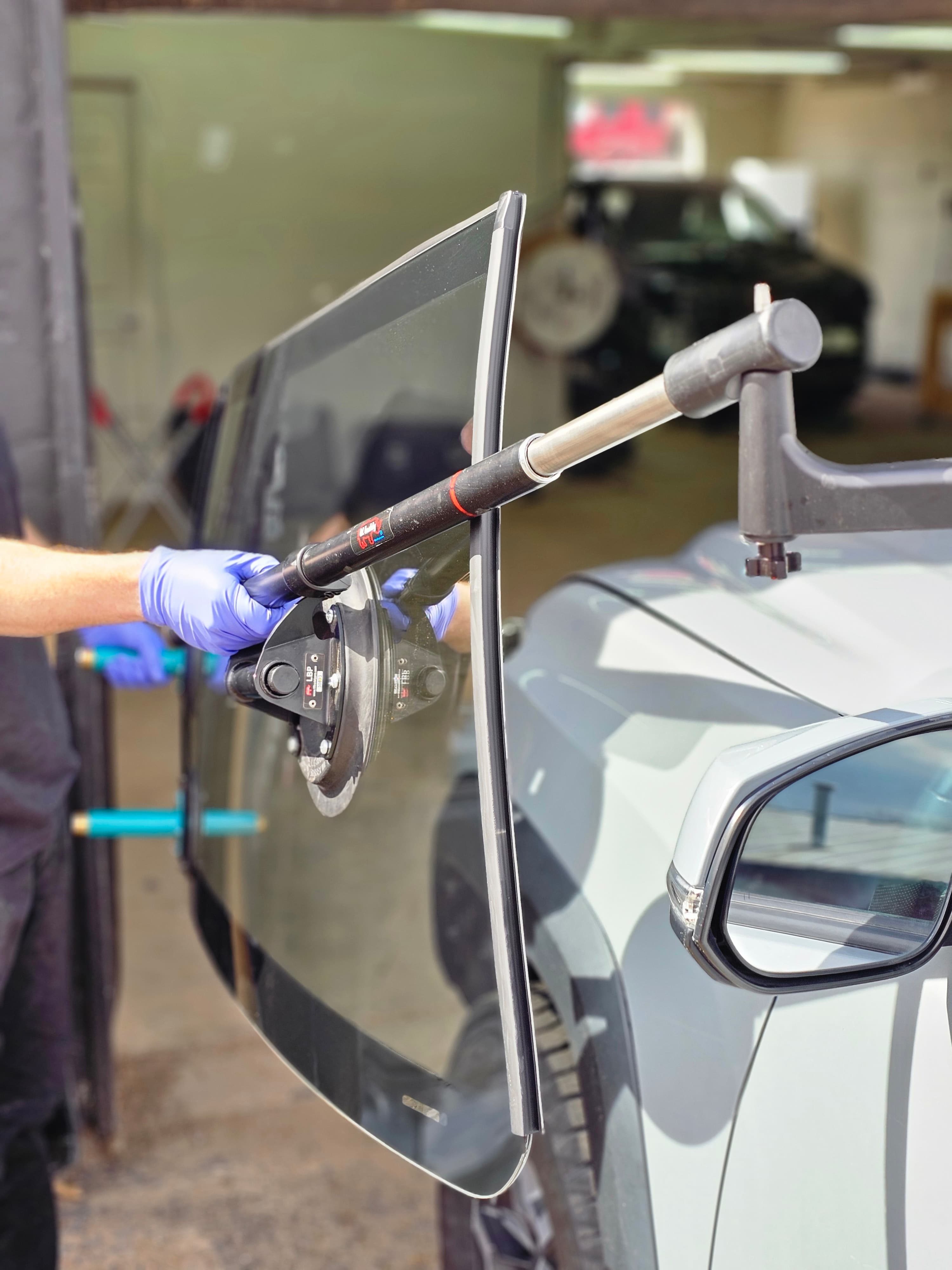 Technician applying urethane adhesive during windshield installation